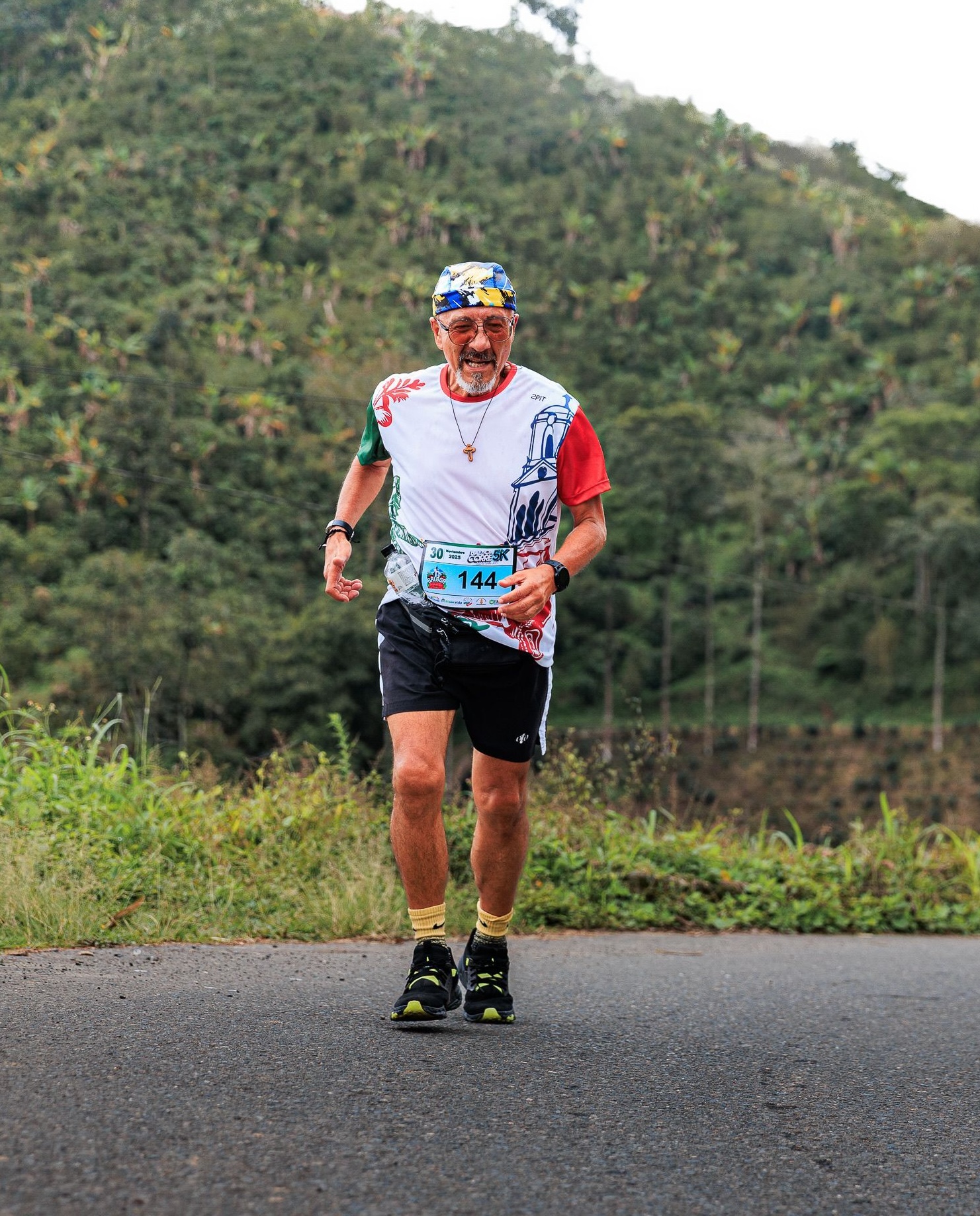 Smiling member running a road race through green hills
